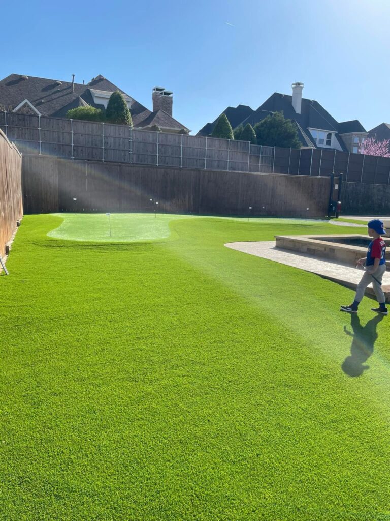 Large backyard in Carrollton, TX covered with artificial grass and a putting green